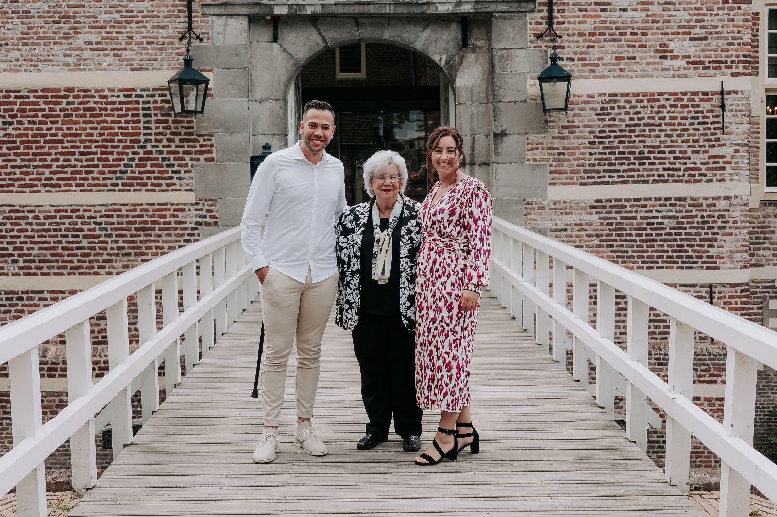 Sven met zijn oma en familie op een brug bij een oud gebouw