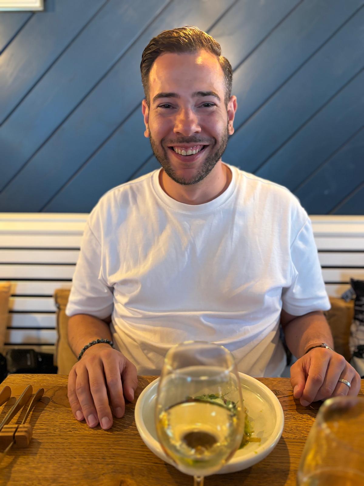 Sven aan tafel bij Ultimo met een glas witte wijn en een voorgerecht
