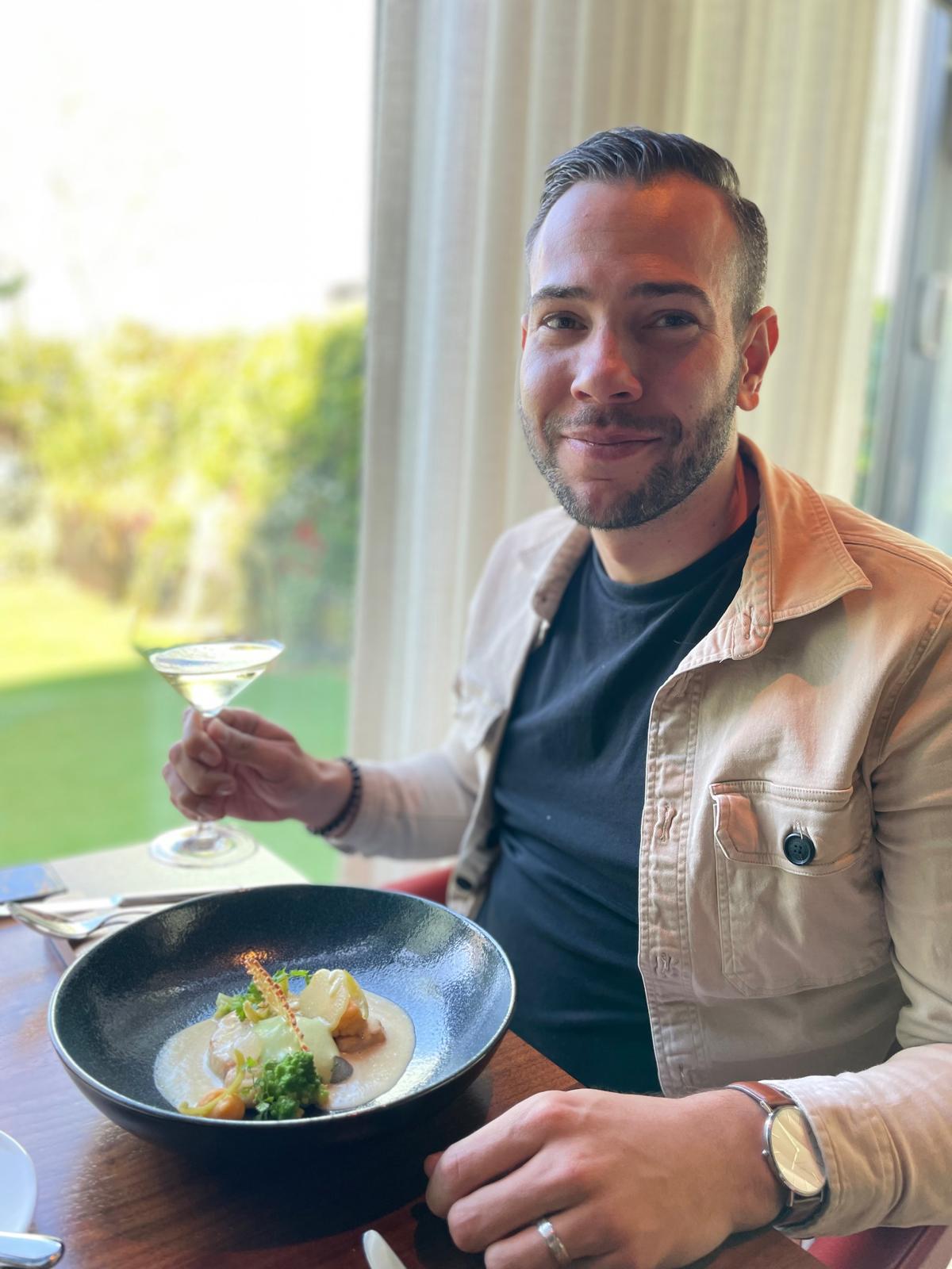 Sven aan tafel bij De Portier met een glas wijn en een verfijnd visgerecht