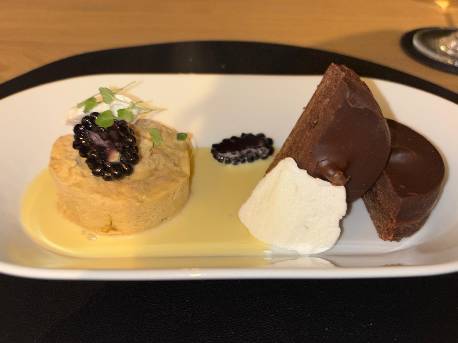 Dessert met parfait, bramen, meringue en chocolade op een langwerpig bord