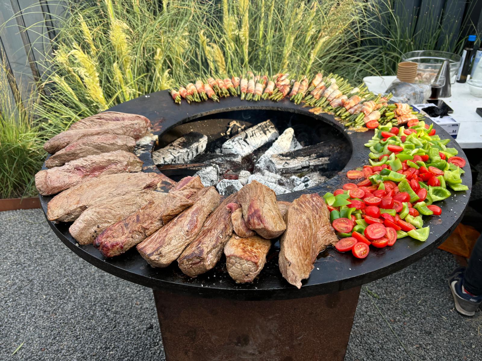 Vuurring met mooie stukken vlees, gegrilde groenten en met spek omwikkelde bundeltjes