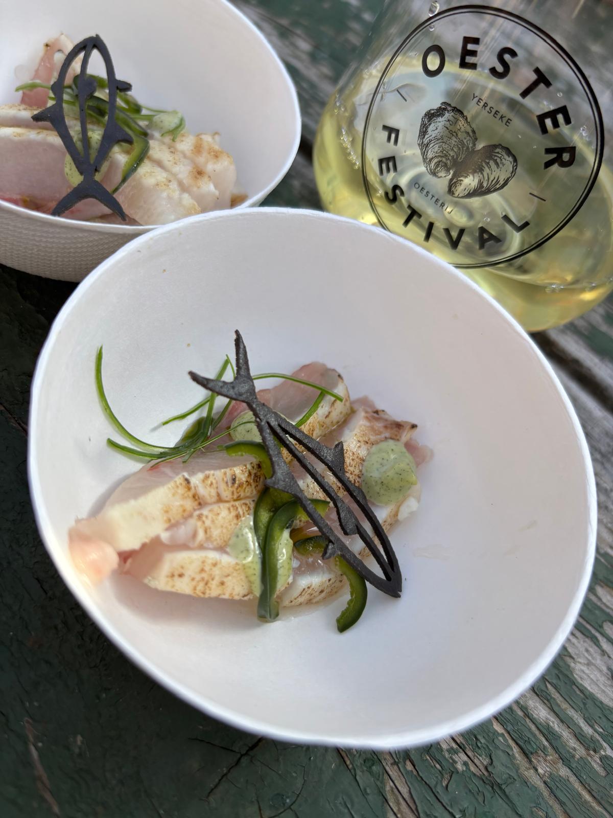 Fris visgerecht met kruiden en een glas witte wijn van het Oesterfestival