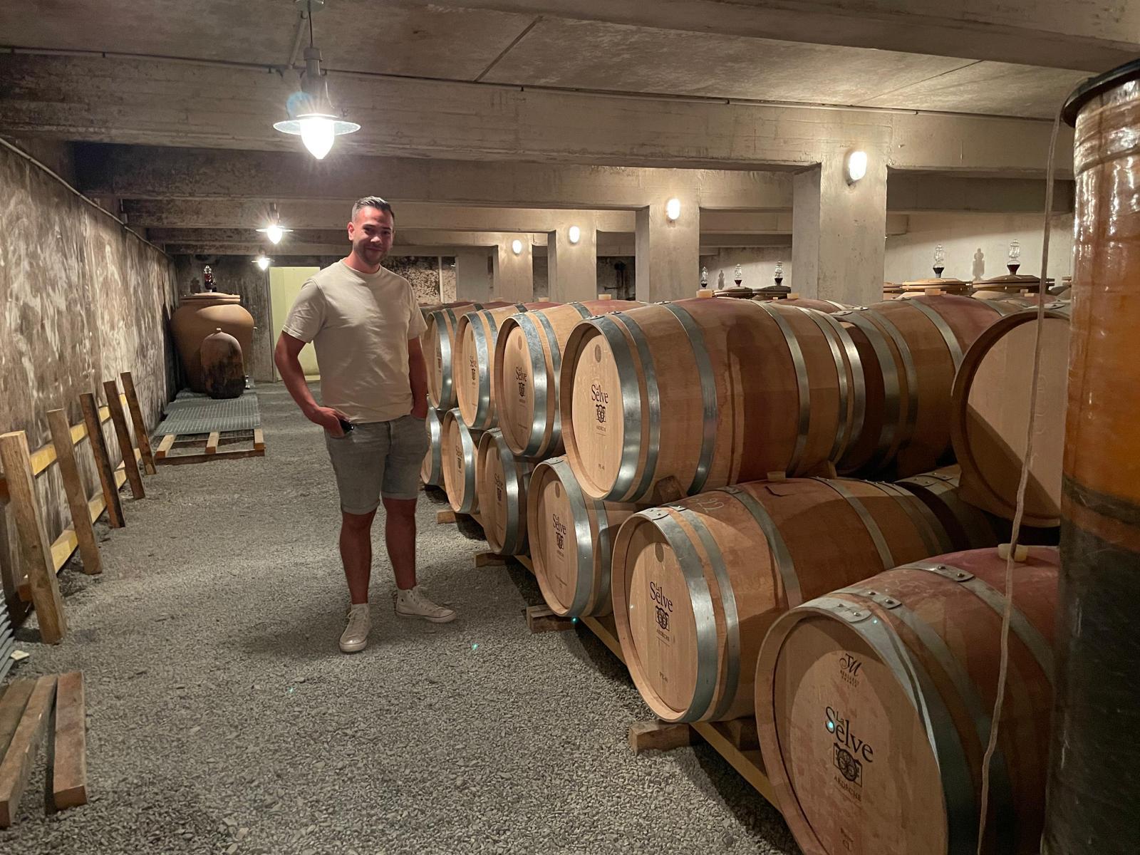Sven tussen de houten wijnvaten in de kelder van Château de la Selve