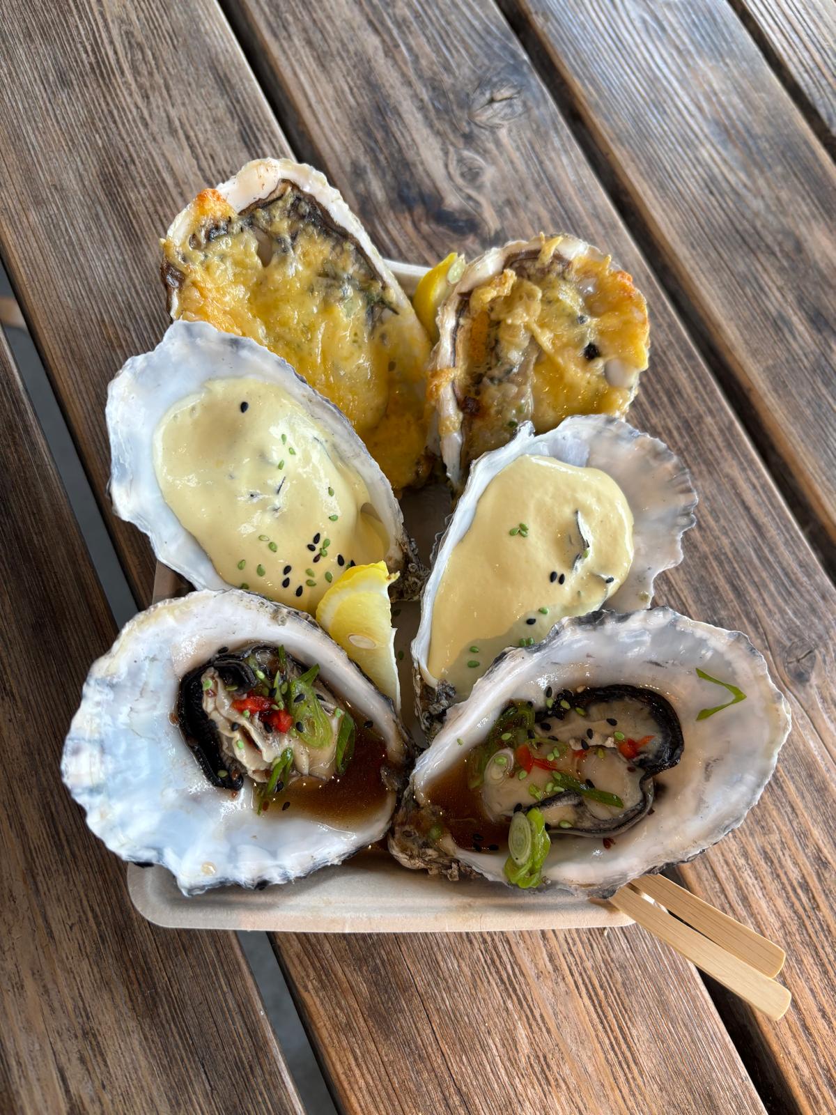 Verschillende warme en creatief bereide oesters op een houten plankje