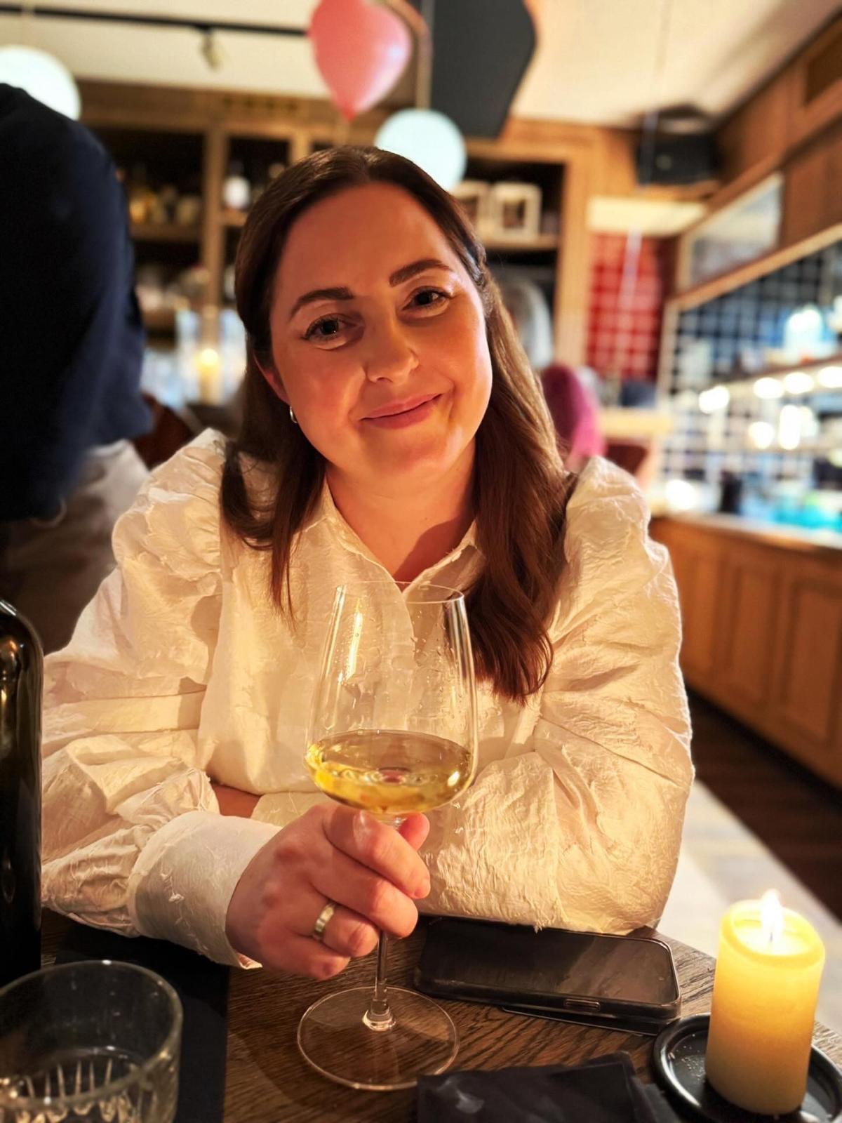 Eva met een glas witte wijn aan een gedekte tafel