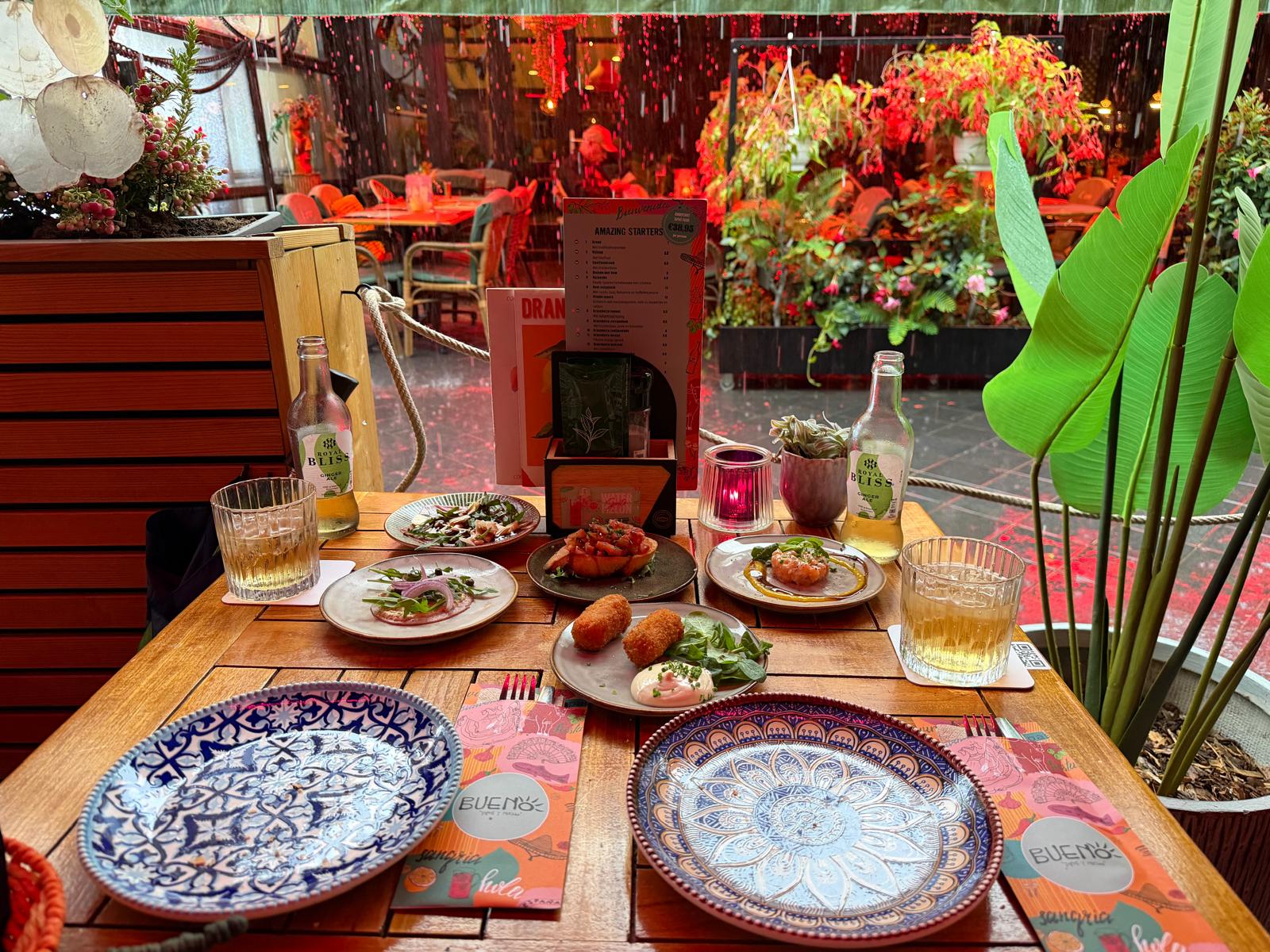 Tafel vol Spaanse tapas onder de luifel bij Buenos in Valkenburg, terwijl het buiten regent