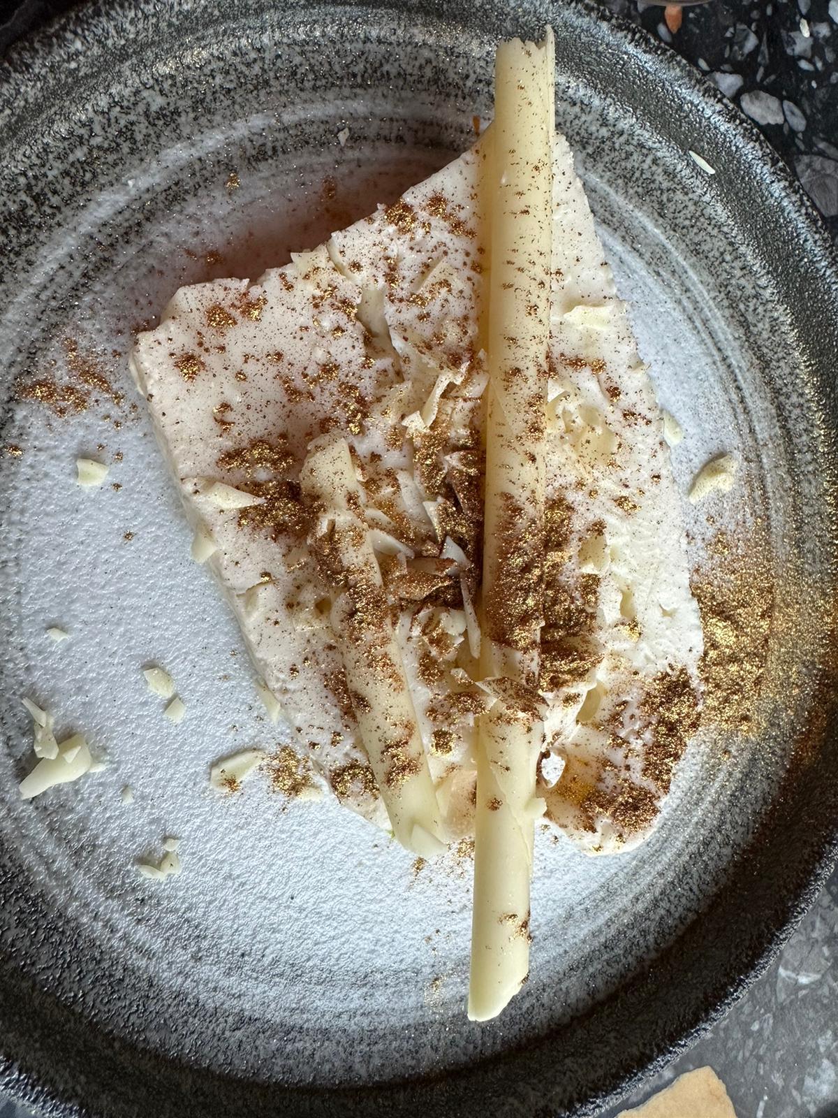 Stella-kaas met witte chocolade en bladgoud op een grijs aardewerken bord