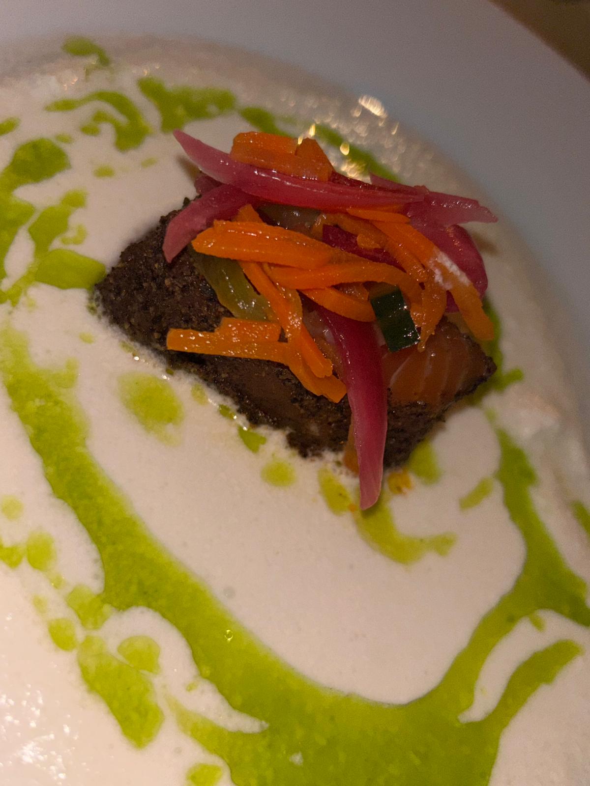 Zalm met krokante korst, gemarineerde groenten en een schuimige saus met kruidenolie
